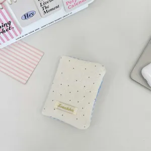 Primo piano di un porta passaporto color crema a pois con bordo a quadretti azzurri
