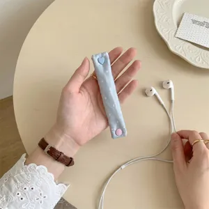 Dettaglio di un ferma cavo a pois blu chiaro con bottoni a pressione a forma di cuore