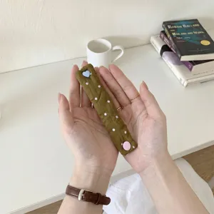 Primo piano dell'organizer per cavi a pois verde oliva con bottone a cuore blu