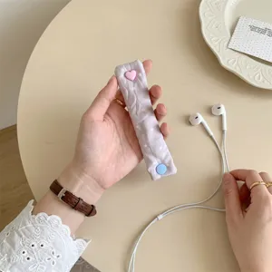 Primo piano di un fermacavo in tessuto a pois viola con un bottone a scatto a cuore rosa