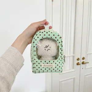 Close-up of a mint green polka dot plush doll display pouch with a clear window