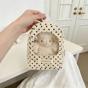 Detail view of a cream polka dot doll storage bag featuring a clear display window