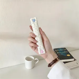 Dettaglio dell'organizzatore cavi imbottito a pois con bottone a pressione a cuore