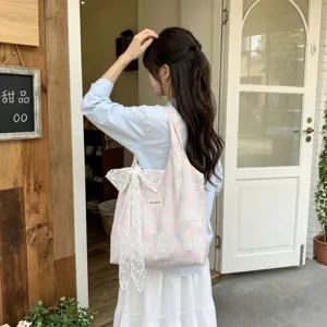 Detail view of pink and blue checkered canvas tote bag with a delicate lace bow