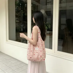 Girl carrying a pink and white striped tote bag with delicate heart embroidery
