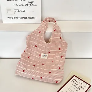 Detail view of pink and white striped tote bag featuring delicate red heart embroidery motifs