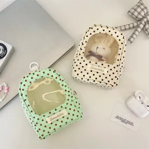 Detailed view of polka dot doll storage bags with transparent windows and D-ring hangers