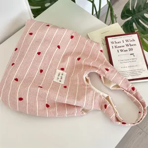Detailed view of the pink and white striped tote bag with red embroidered heart patterns