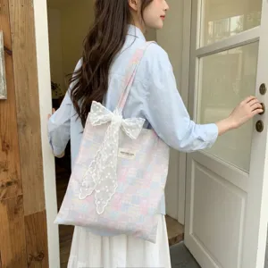 Detail of pink and blue plaid canvas tote bag featuring a delicate white lace bow.