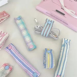 Dettaglio di fascette fermacavi scozzesi macaron con bottoni automatici a cuore per cavi