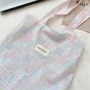 Close-up of a pink and blue plaid canvas tote bag with cute stars and bows patterns
