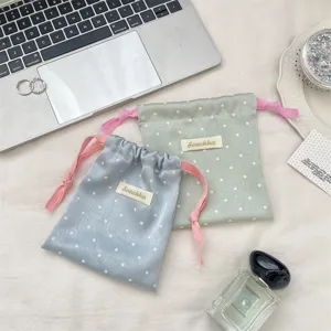 Detailed view of polka dot satin drawstring bags with contrasting pink cords.