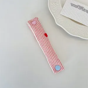 Primo piano di un fermacavo in tessuto a righe rosse con bottone a pressione a cuore