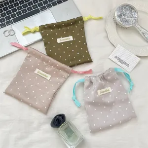 Close-up of three macaron satin polka dot drawstring pouches with contrasting rope.
