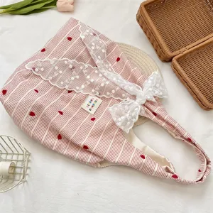 Detail of pink striped tote bag with red heart embroidery and white lace bow