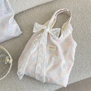 Detail of a pink and blue plaid tote bag with a large white lace bow decoration