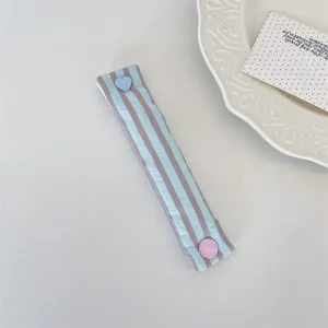 Dettaglio del cinturino fermacavi a righe macaron con bottone a pressione a cuore