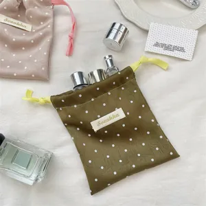 Olive green polka dot satin drawstring pouch shown with travel-sized cosmetic bottles