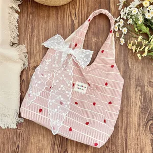 Detail view of pink and white striped tote bag with lace bow and heart embroidery.