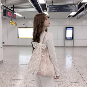 Side view of a pink floral embroidered tote bag with a large white lace bow.