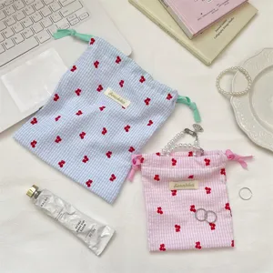 Primer plano de bolsas de algodón a cuadros con bordado de cerezas rojas y etiquetas.