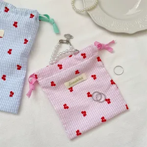 Primer plano de bolsa de cuadros con bordado de cerezas y accesorios de joyería
