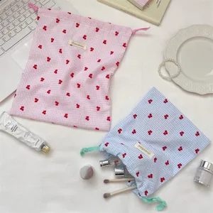 Vista detallada de las bolsas de tela con cordón bordadas con cerezas para cosméticos.