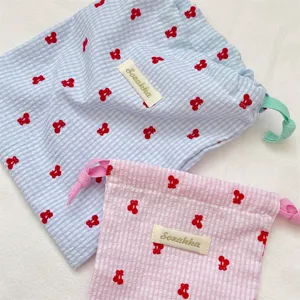 Primer plano de bolsas de almacenamiento a cuadros con bordados de cerezas y etiqueta Sozakka