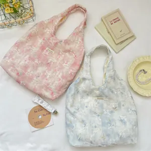 Close-up of pink and blue floral embroidered vest tote bags on white background