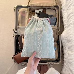 Detailed view of mint green floral embroidered drawstring pouch for travel organization.