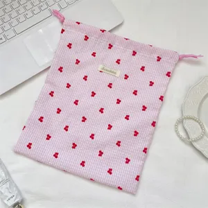 Vista detallada de bolsa con cordón de cuadros rosas con bordado de cerezas viaje