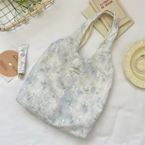 Detail view of light blue tie-dye tote bag with white floral embroidery and Sorakka tag
