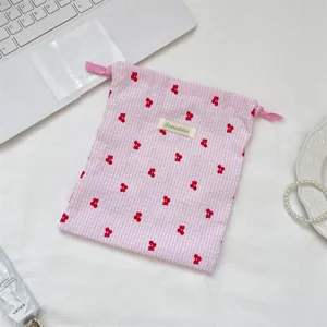 Detalle de una bolsa de almacenamiento de cuadros rosas con bordado de cerezas rojas