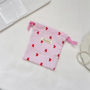 Detalle de una bolsa de almacenamiento con cordón a cuadros rosas y bordado de cerezas