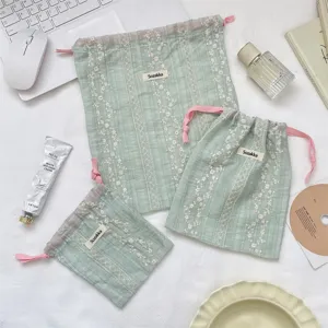 Detailed view of three light green floral embroidered drawstring storage pouches