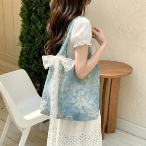 Detail of a floral tote bag featuring a large white lace bow in a cozy cafe setting.