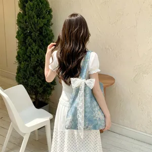 Korean style blue floral tote bag with a large white lace bow detail worn on shoulder.