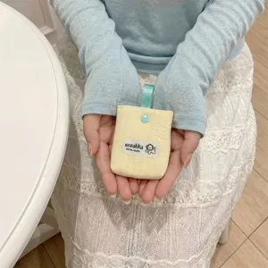 Close-up of a cream yellow quilted storage pouch for earphones held in person's hands.