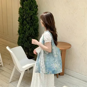 Model carrying a blue rose floral tote bag with lace ribbon detail in a cafe setting