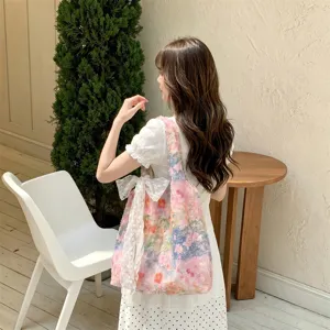 Close-up of a pink floral tote bag with a lace bow carried by a model in a room