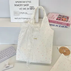 Crème canvas draagtas met stippen en een decoratieve kanten strik in lifestyle-setting.