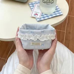 Gros plan d'un panier de rangement bleu en tissu avec des nœuds et bordure en dentelle
