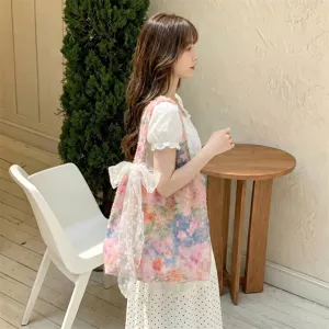 Floral tote bag with large lace bow worn by model in a stylish, minimalist indoor setting.