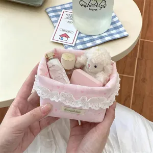 Vue détaillée du panier de rangement en tissu rose avec bordure en dentelle.