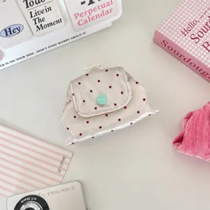 Gedetailleerd bovenaanzicht van een kleine satijnen tas met stippen en een muntgroene knop