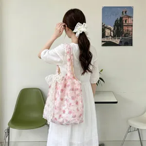 Floral pink tote bag with lace bow detail shown on shoulder in lifestyle setting