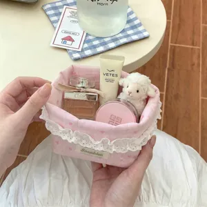Gros plan d'un panier de rangement rose en tissu avec cœurs et dentelle blanche