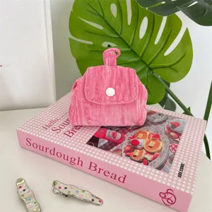 Close-up van een roze corduroy mini opbergzakje met witte knoop op een decoratief boek