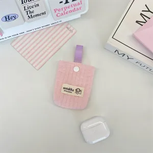 Close-up view of a pink quilted earphone storage pouch featuring a purple strap