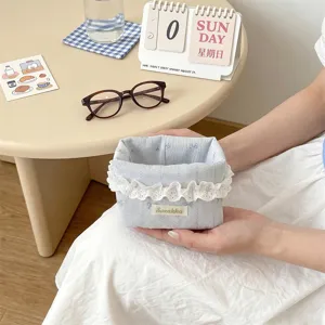 Petit panier de rangement en tissu bleu avec dentelle pour bien organiser le bureau.
